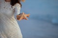 Closeup on woman on seashore at sunset showing starfish