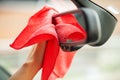 Closeup of woman wiping car interior with red rag.