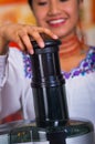 Closeup woman's hands using juice maker, pressing down plastic part inserting carrot into machine, healthy lifestyle