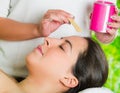 Closeup womans face receiving facial hair waxing treatment, hand using wooden stick to apply wax, beauty and fashion Royalty Free Stock Photo