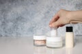 Closeup of womans hand holding skin cream Tonicum, moisturizer bottles and jar with Himalayan salt on white table. Grunge blurred