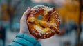 Closeup of a womans hand holding a soft pillowy pretzel covered in salt and mustard