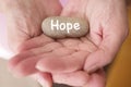Closeup of womans hands holding stone with the word hope