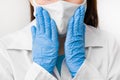 Closeup womans hands to the face in protective mask against coronavirus, SARS-CoV-2, 2019-nCoV or flu. Doctor in white labcoat,
