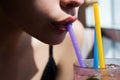 Closeup of womans lips drinking with pink straw. Woman drink cocktail. Close up wet sexy lips.