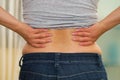 Closeup womans lower back with shirt lifted up, wearing jeans, holding hands on hips, weightloss concept Royalty Free Stock Photo