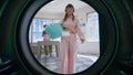 Closeup woman put laundry in machine. Young hipster using public laundromat