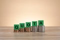 Closeup of wooden blocks with "QUOTA" lettering on stacked coins