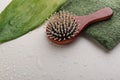 Closeup of wooden brush, green topical leaf and towel on the empty beige surface