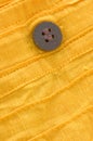 Closeup of wooden button on yellow organic cotton