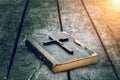 Closeup of wooden Christian cross on bible on the old table.