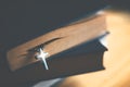 Closeup of wooden Christian cross necklace next to holy Bible Royalty Free Stock Photo