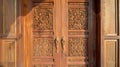 A closeup of a wooden door adorned with intricately carved patterns hints at the incorporation of traditional