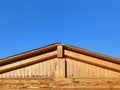 Closeup of wooden facade and roof under blue sky. New rural wooden house fragment with roof. Wooden beam structure. Architecture Royalty Free Stock Photo