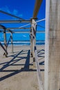 Closeup of wooden posts and beams of an abandoned structure on the beach with the sea with small waves and foam in the background