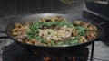 Closeup of a woodfired paella being prepared