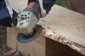 Work with angle grinder machine and wooden plank from pine for log house ceiling Royalty Free Stock Photo