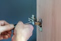 Closeup of worker`s hands fitting wardrobe hinge doors in closet Royalty Free Stock Photo