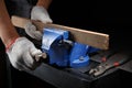 Workers hands on a wooden plank locked in the iron vise