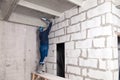 Closeup of working builder working on a wall of gray aerated concrete with rough seams with mortar and ceiling with foam. Concept