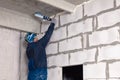 Closeup of working builder working on a wall of gray aerated concrete with rough seams with mortar and ceiling with foam. Concept Royalty Free Stock Photo