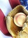 Closeup of worn baseball and mitt on a US flag background, great for America`s favorite pasttime. Vertical image. Royalty Free Stock Photo