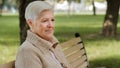 Closeup wrinkled face of 65s happy elderly woman outdoors looking aside having wide smile, dental implants and Royalty Free Stock Photo