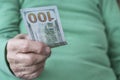 Closeup wrinkled hand holding a hundred american dollar banknote