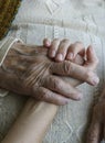 Closeup wrinkled hand holding a younger hand Royalty Free Stock Photo