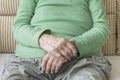 Closeup wrinkled hands of a senior person sitting on a sofa