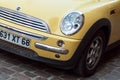 Closeup of Yelllow mini Cooper front parked in the street