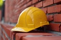 closeup yellow construction safety helmet on red brick wall