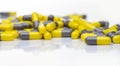 Closeup yellow and gray capsule pills on white background. Prescription drugs. Pharmaceutical industry. Health and medical care