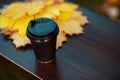 Closeup on yellow leaves and cup of coffee on bench