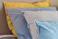 Closeup of Yellow and light blue pillows in a row on the bed, modern retro decoration for home, pastel light colors colorful Royalty Free Stock Photo