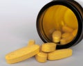 Closeup of yellow medical pills spilling out of a  glass drugs bottle. Royalty Free Stock Photo