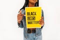 Closeup of a yellow poster with text Black Lives Matter against violence in hands of African American woman. Black lives matter