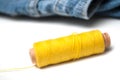 yellow sewing thread spool bobbin on white table on blue jeans background Royalty Free Stock Photo