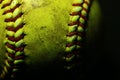 Yellow softball closeup with red seams on black background. Royalty Free Stock Photo