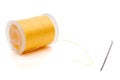 Closeup of a yellow spool of thread and a needle