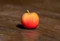 Closeup of a yellowish-red apple on the wooden table.