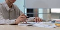 Closeup of a young accountant using a calculator to calculate currency and company numbers at his desk in the office. Royalty Free Stock Photo