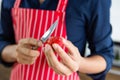 Closeup of young asian man with red apron cutting strawberry in left hand