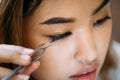 Asian woman placing decorative eyelashes on eye