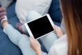 Closeup young asian woman sitting and using mockup of tablet computer with display blank screen on sofa. Royalty Free Stock Photo