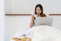 Closeup of young Asian woman working on bed while have a breakfast in the morning. Technology and lifestyle concept Royalty Free Stock Photo