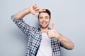 Closeup of young, attractive, happy, creative, cheerful guy making frame with fingers in front of face, looking at camera over g