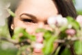 Closeup of young attractive woman looking thru blooming branches