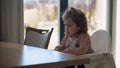 Closeup of young baby in white feeding high chair, kid is trying to eat himself, happy child with food stained face Royalty Free Stock Photo