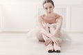 Closeup of young ballerina sit in pointe shoes on white floor background Royalty Free Stock Photo